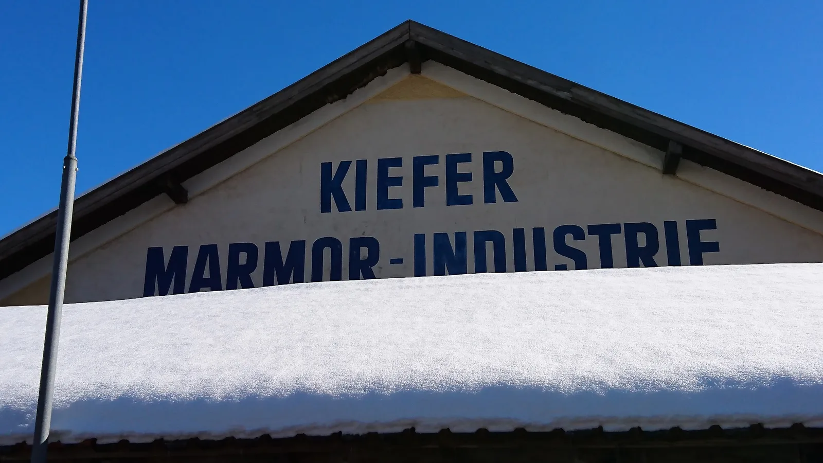 Giebel des Werksgebäudes mit der gemalten dunkelblauen Aufschrift KIEFER MARMOR-INDUSTRIE