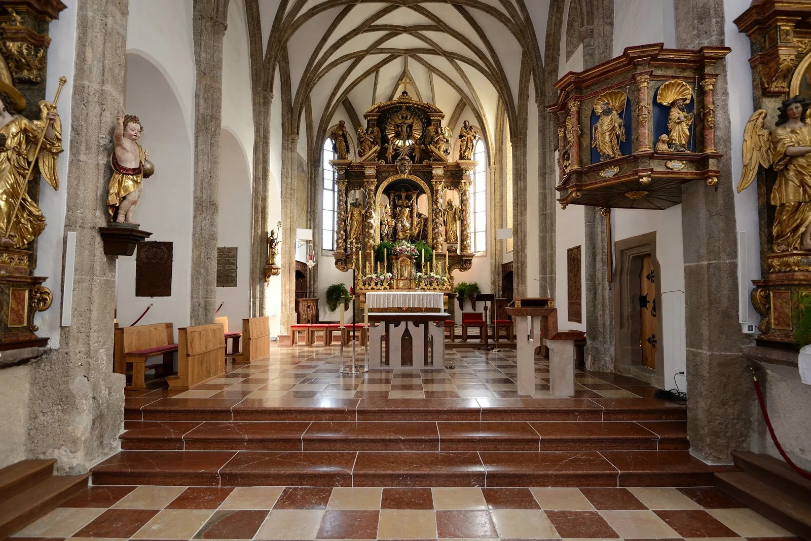 Kircheninnenraum in Abtenau mit verlegtem Boden aus rotem und weißem Marmor, Blick durch das Mittelschiff zum Altar