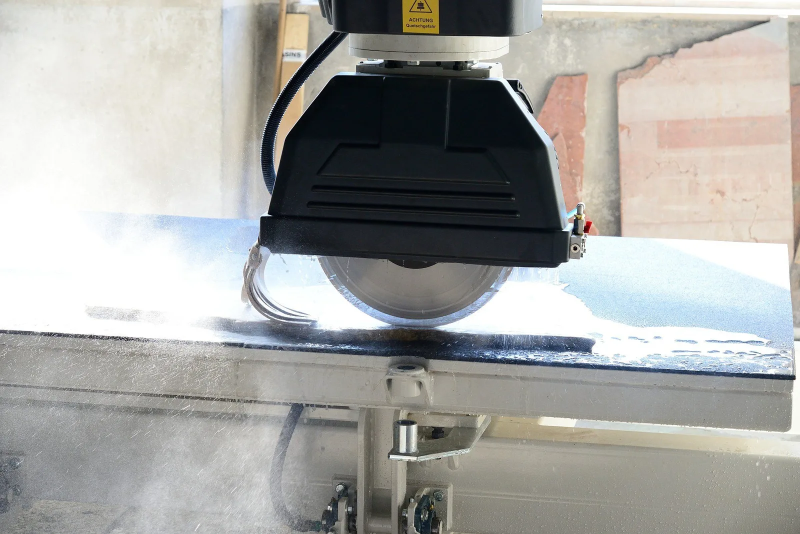 Brückenfräse mit rundem Sägeblatt beim Schneiden einer hellen Steinplatte im Werk
